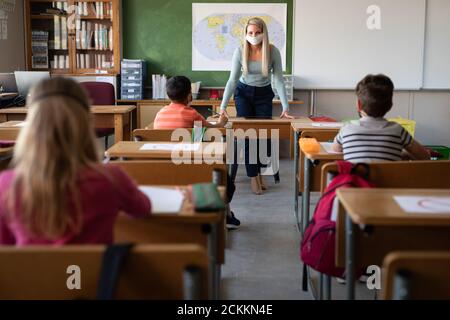 Insegnante di sesso femminile che indossa maschera di insegnamento in classe a scuola Foto Stock