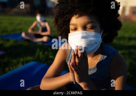 Ragazzo che indossa la maschera facciale che esegue yoga in giardino Foto Stock