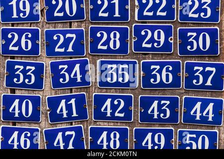 Set di targhette blu con incremento del numero civico rispetto a una vecchia sfondo di legno Foto Stock