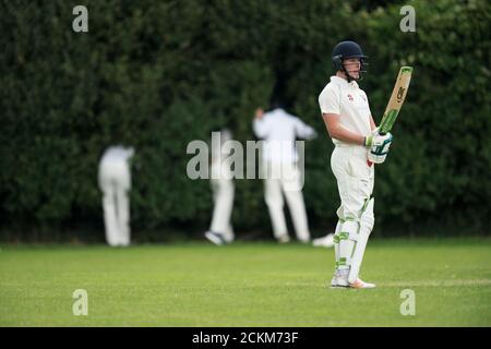 Cricket batsman in attesa dei fielder di trovare la palla che ha colpito per sei. Foto Stock