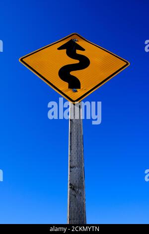 Curve più avanti sul cartello stradale segno giallo brillante su blu cielo Foto Stock