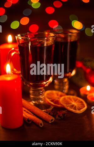 VIN brulé con bastoncini di cannella, candele d'arancia, ramo di abete e baubles sopra natale sfondo luci Foto Stock