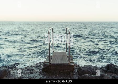 Pier fuori all'oceano sulla spiaggia con pietre Foto Stock