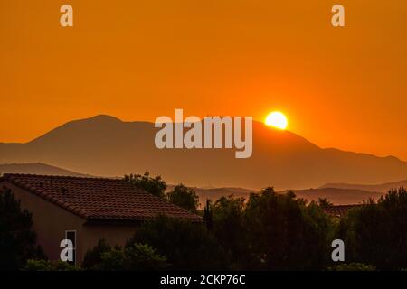 Drammatica alba filtrata attraverso il cielo pieno di fumo sopra la montagna di Saddleback nella Foresta Nazionale di Cleveland, Orange County, mentre i fuochi d'oro continuano a bruciare fuori controllo in California . Foto Stock