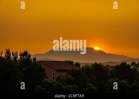Drammatica alba filtrata attraverso il cielo pieno di fumo sopra la montagna di Saddleback nella Foresta Nazionale di Cleveland, Orange County, mentre i fuochi d'oro continuano a bruciare fuori controllo in California . Foto Stock