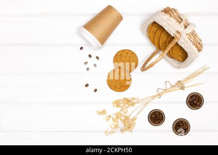 Biscotti di farinata d'avena con tazza di caffè di carta su tavola di legno bianco. Spazio di copia. Dessert sano rustico. Dolci per il caffè Foto Stock