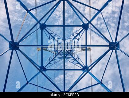 Industria elettrica, vista dal basso su supporta linee elettriche ad alta tensione contro il cielo Foto Stock