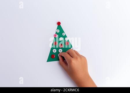 Albero di Natale fatto di carta e bottoni. Disposizione piatta. Concetto di vacanza. Artigianato semplice per i bambini Foto Stock