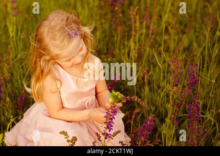 Bella ragazza bionda in fiore prato Foto Stock