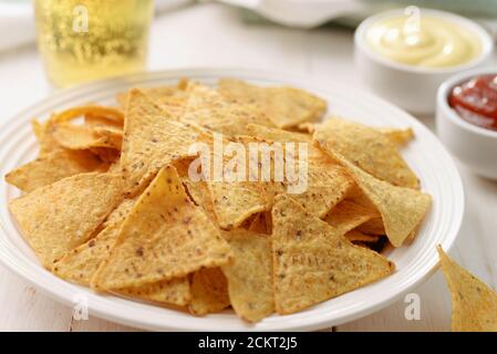 Piatto di nacho di patatine di mais e salse su fondo di legno Foto Stock