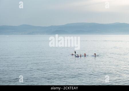 PORTONOVO, SPAGNA - 11 AGOSTO 2020: Un gruppo di giovani si diverte a praticare il paddle surf nella Ria de Pontevedra in una giornata estiva. Foto Stock