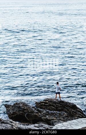 PORTONOVO, SPAGNA - 7 AGOSTO 2020: Pescatore solitario che pesca sul mare in una tranquilla serata chiara nel Rias Baixas in Galizia, Spagna. Foto Stock