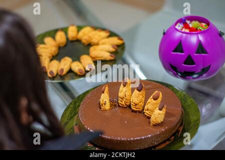 Festa della torta al cioccolato di Halloween con le dita e lo sfondo di biscotti cuted zucca viola e piatto di dita Foto Stock