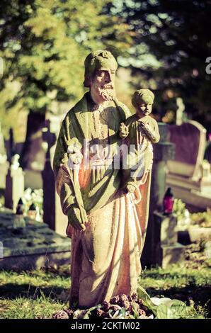 statue di pietra tra tombe nel cimitero Foto Stock