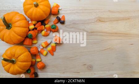 Le zucche in miniatura e l'autunno mescolano il mais caramella su uno sfondo di legno. Modello con spazio di copia per la stagione autunnale o di Halloween Foto Stock