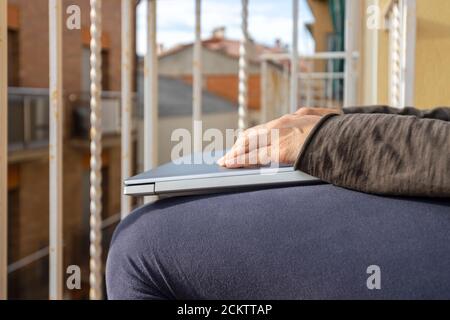 Donna con computer portatile sul balcone a casa. Ufficio domestico. Foto Stock