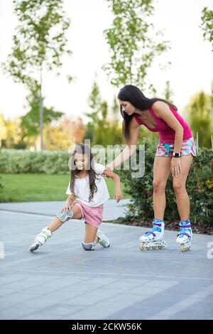 la bambina è caduta giù mentre rotola con la madre nel parco. mamma aiuta la figlia a alzarsi dopo la caduta Foto Stock