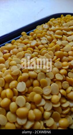Piselli spezzati gialli isolati su piastra viola con fondo bianco piatto con messa a fuoco selettiva. Foto Stock