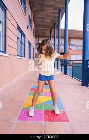 Ritorno a scuola. Bambini che corrono e saltano in cortile con maschera facciale Foto Stock