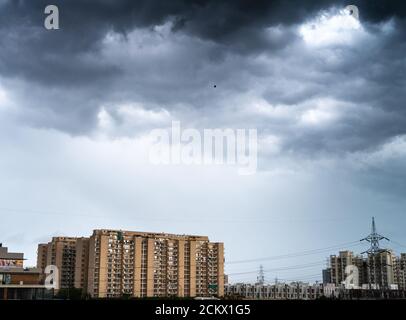 il paesaggio urbano di gurgaon delhi con le nuvole monsonone che gettano ombre in alto sorgono appartamenti ed edifici che mostrano il passare del tempo e rapidamente crescita di reale Foto Stock