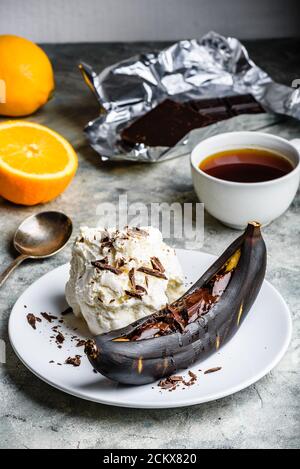 Banana alla griglia con cioccolato fondente e gelato alla vaniglia. Foto Stock