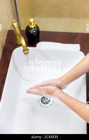 Donna lavando e disinfettando le mani con sapone e acqua calda come parte dei protocolli di prevenzione e protezione del coronavirus; smettere di diffondere l'igienizzazione covid-19 Foto Stock