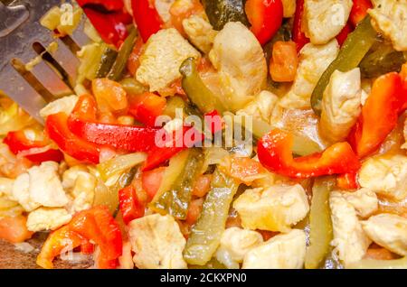 Nel calderone fritti pezzi di carne di pollo, peperoni rossi, pomodori, sottaceti, cipolle bianche Foto Stock