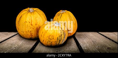 Tre zucche autunnali gialle su tavola di legno. Foto Stock