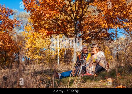 Passeggiata nella stagione autunnale. La coppia anziana si agguanava seduto nel parco. Uomo e donna si rilassano all'aperto Foto Stock