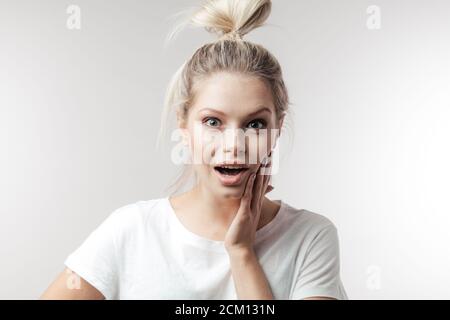 Eccitato giovane donna caucasica guarda con sorpresa stupito espressione e respiro bato, sfondo bianco per la vostra pubblicità o testo promozionale Foto Stock