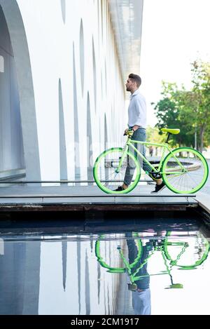 Vista laterale di un giovane uomo bearded che cammina con fixie bicicletta Foto Stock