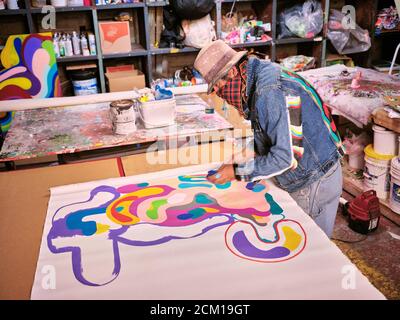 Un artista con rivestimento facciale crea l'arte nel suo spazio studio. Foto Stock