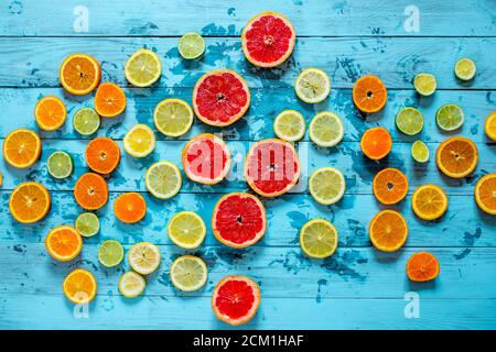 Composizione di arance di sangue limone, lime, pompelmo, mandarino. Intero, tagliato a metà, sbucciato, e affettato disposto su tavole blu di legno. Concetto antiossidante. Foto Stock