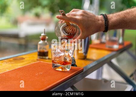 Barman versa whiskey in un vetro al bar. Foto Stock