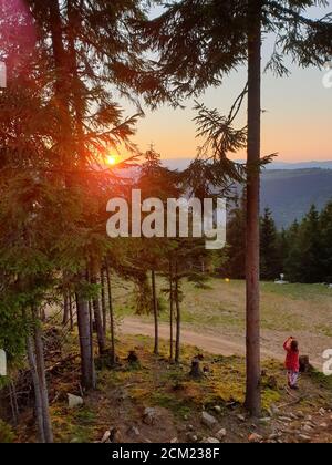 Giovane ragazza scattando foto con telefono tramonto in montagna, in Marisel, Cluj contea, Transilvania, Romania. Attività all'aperto in natura mentre sociale Foto Stock