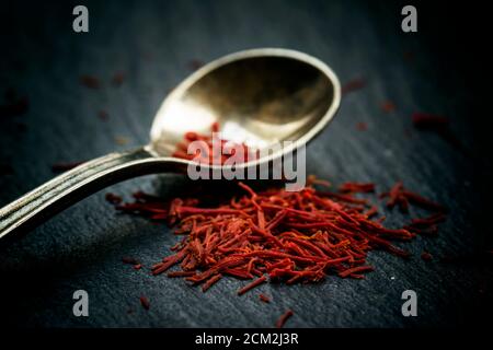 Lo zafferano in un cucchiaio su uno sfondo scuro, il fuoco selettivo, macro shot, profondità di campo Foto Stock