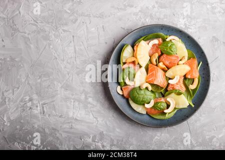 Salmone fresco con ananas, spinaci e anacardi su fondo grigio in cemento. Vista dall'alto, spazio per la copia, disposizione piatta. Foto Stock