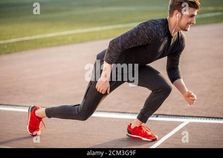 Giovane atleta maschio lanciando la linea di partenza in gara via Foto Stock