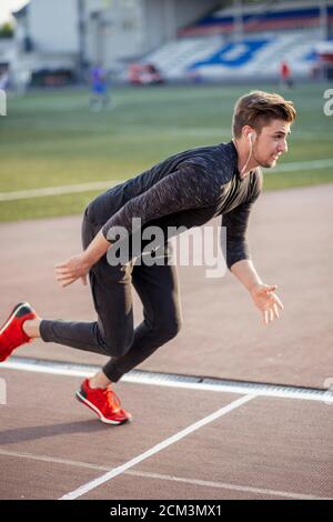 Giovane atleta maschio lanciando la linea di partenza in gara via Foto Stock