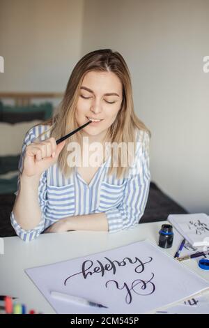 Ritratto di giovane bella signora seduta al banco bianco e. pensate alla calligrafia Foto Stock