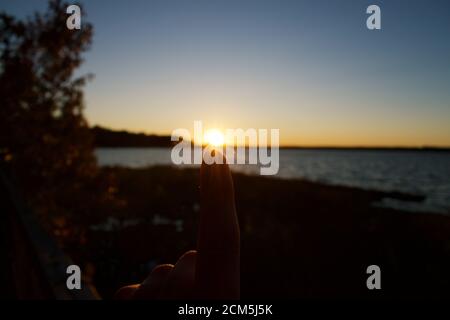 Tramonto sulla Baia di Belmont con silhouette di alberi e. scogliera Foto Stock