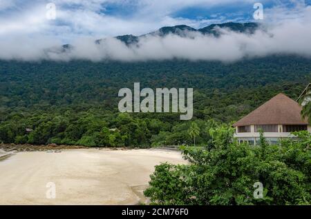 ampia spiaggia di sabbia circondata da vegetazione verde tempestosa Foto Stock