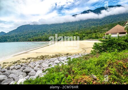 ampia spiaggia di sabbia circondata da vegetazione verde tempestosa Foto Stock