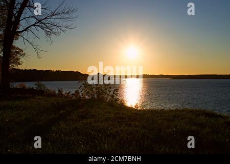 Tramonto su Belmont Bay con silhouette arida ramo albero e riva del fiume. Foto Stock