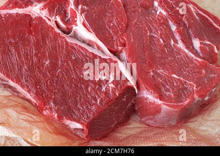 Pezzo fresco carne di manzo cruda su carta da imballaggio. Vista dall'alto Foto Stock