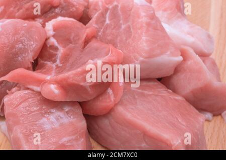 Carne di maiale cruda tagliata su tavola di legno, Tana di pezzetti di maiale crudo, primo piano Foto Stock