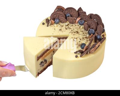 Le mani della donna tagliano la torta. La mano della donna ha tagliato la torta. Fetta di bella torta per una panetteria di famiglia, con biscotti al cioccolato e frutti di bosco decorazione su s. Foto Stock