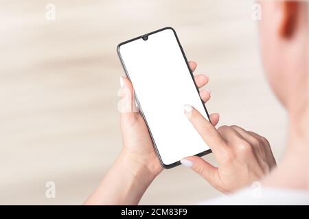 Immagine mockup delle mani di donna che tengono moderno cellulare con schermo vuoto, interno Foto Stock