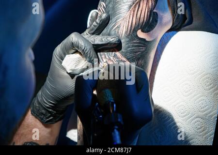 Immagine del tatuatore che fa il tatuaggio nero del serpente per la donna Foto Stock