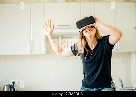 Un lavoratore piuttosto casual che utilizza la cuffia per realtà virtuale in cucina. Foto Stock